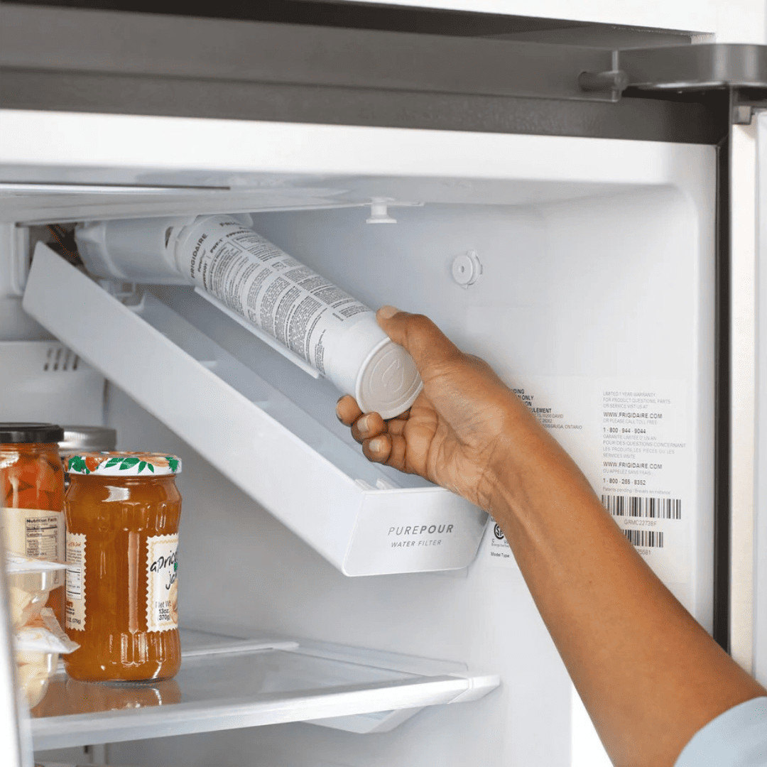 Hand replacing a water filter in a refrigerator.
