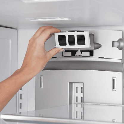 Hand adjusting a refrigerator filter inside a white refrigerator.
